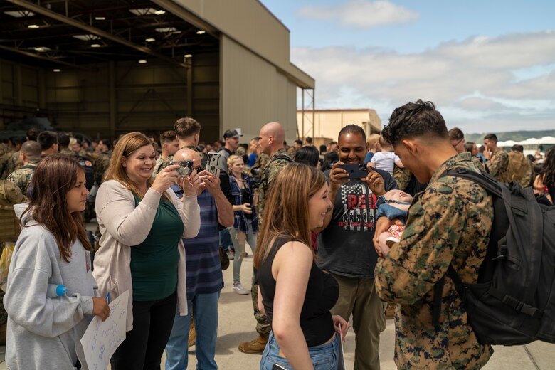A U.S. Marine with Marine Light Attack Helicopter Squadron (HMLA) 369, Marine Aircraft Group 39, 3rd Marine Aircraft Wing, holds his newborn baby after returning from deployment to the Indo-Pacific in support of the Unit Deployment Program and the 31st Marine Expeditionary Unit, at Marine Corps Air Station Camp Pendleton