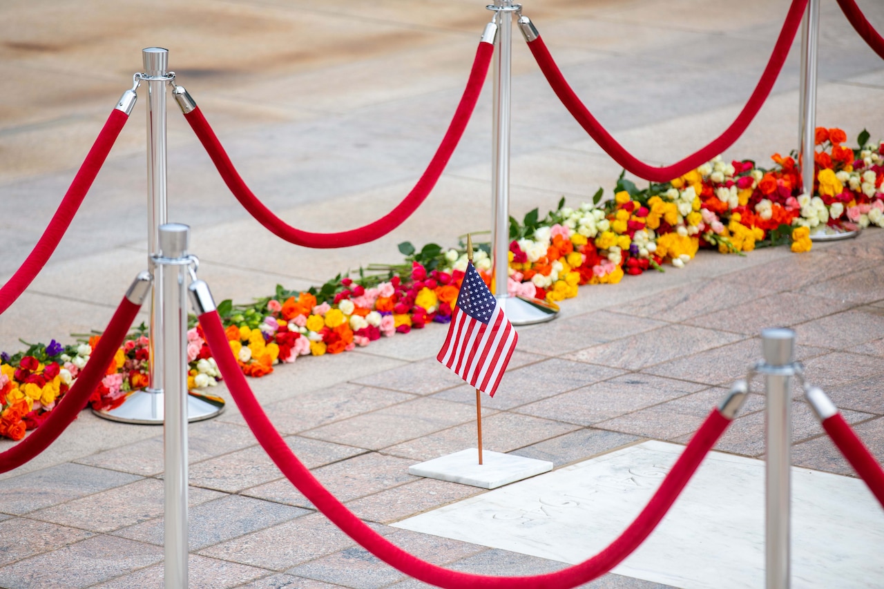 A small American flag sits near a memorial.