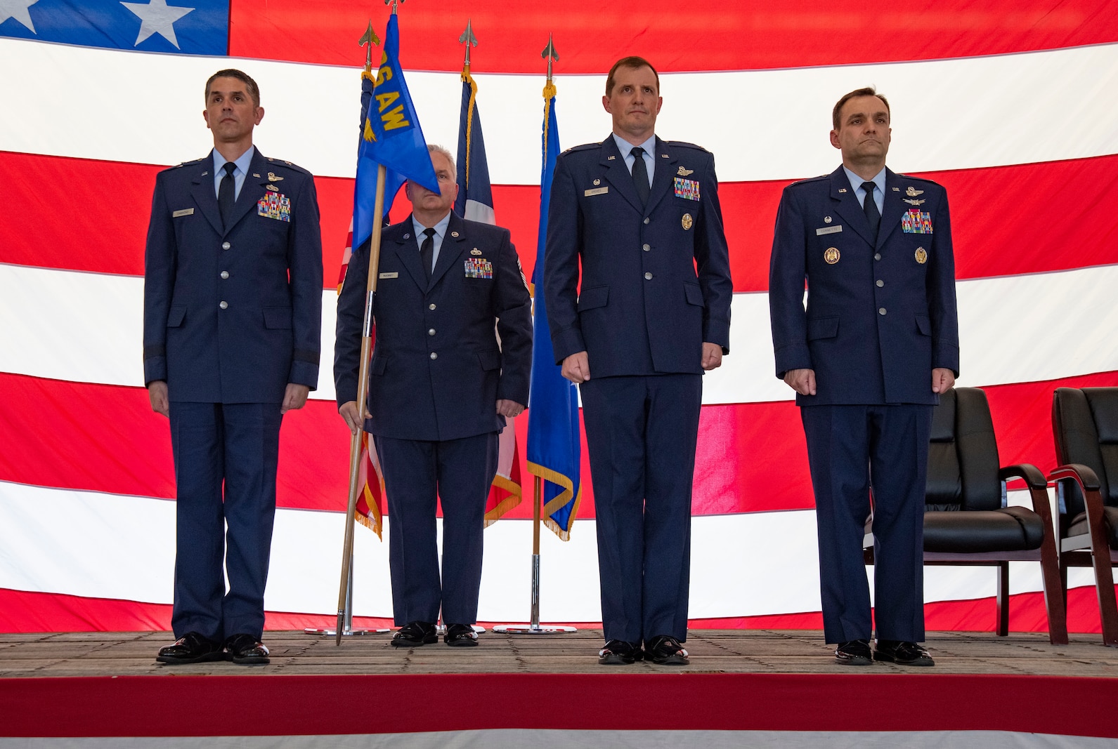 Three Air Force officers and one enlisted chief master sergeant in uniform stand side by side on a stage.