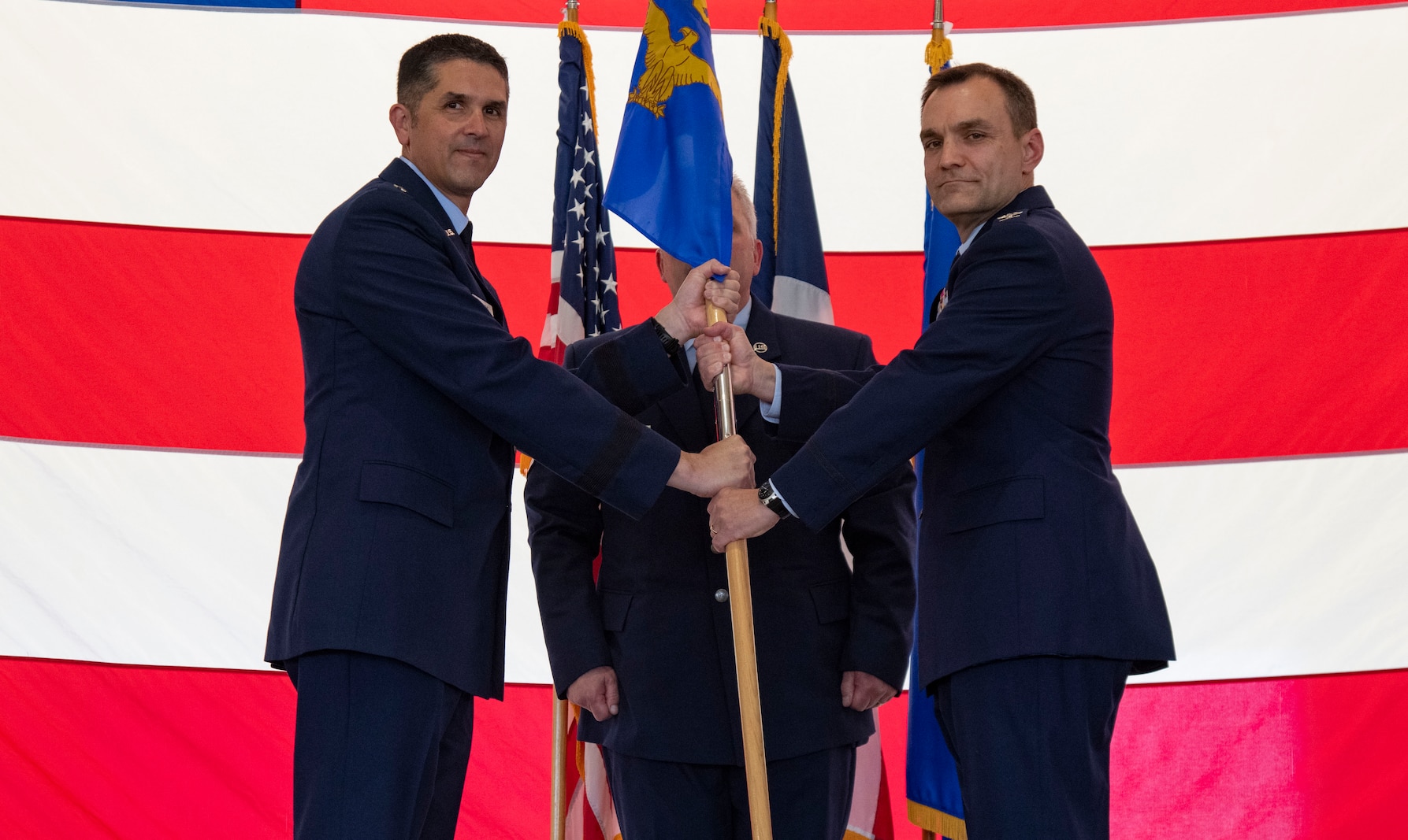 Two Air Force officers in uniform hold up unit guidon.