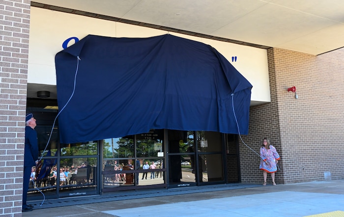 A General and a woman pull on a rope to unveil a building name