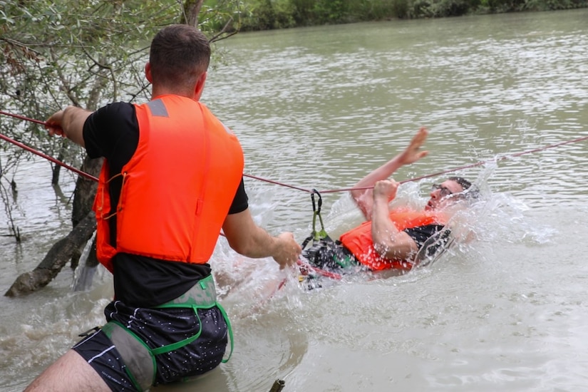 Two service members train together in a body of water.