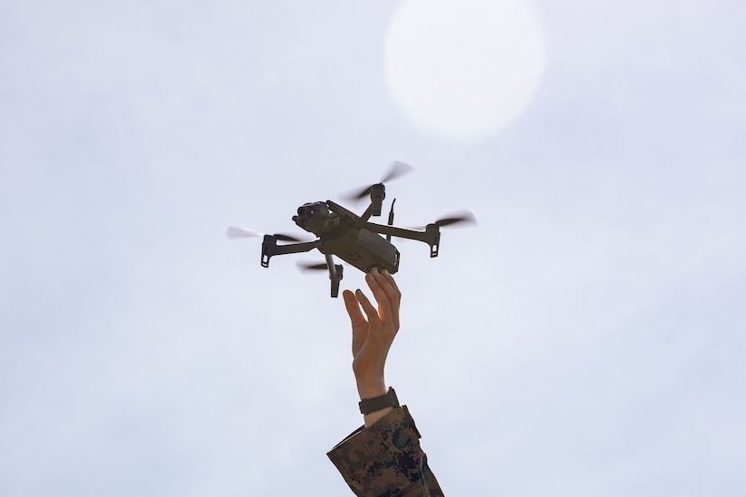 A Marine reaches for a small unmanned aircraft system.