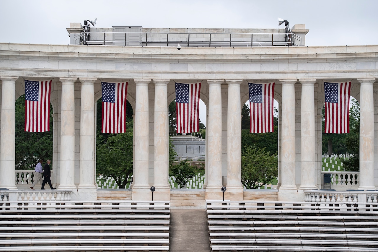 U.S. flags hang between white columns in an amphitheater.