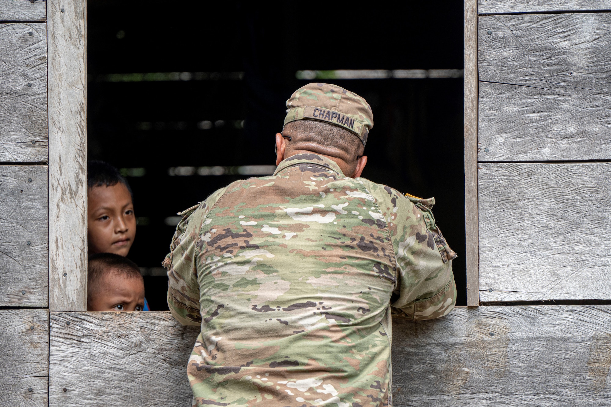 A photo of a soldier talking to a group of children.