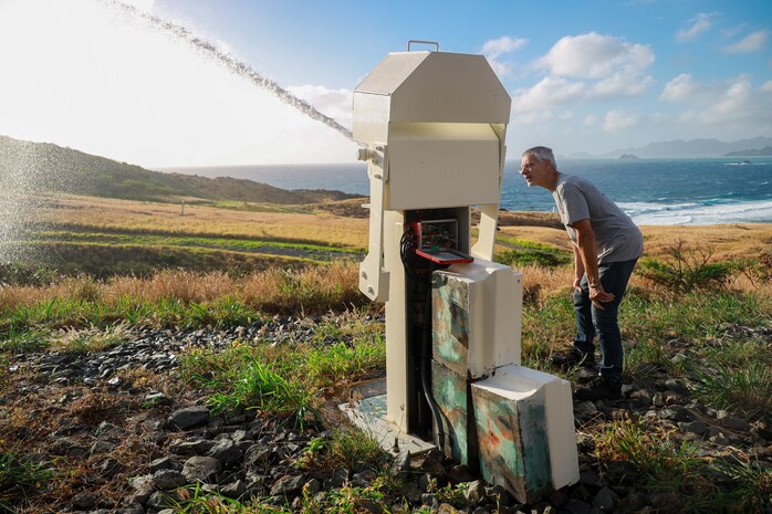 Charles Ronie, a contractor working with Marine Corps Base Hawaii’s Environmental Compliance and Protection Division, inspects a fire-prevention water cannon, MCBH, April 3, 2024. The water cannons, on MCBH’s Crater Range, are a series of remote-controlled devices designed to protect the Ulupa’u Head Wildlife Management Area from potential spot fires. (U.S. Marine Corps photo by Lance Cpl. Carlos Daniel Chavez-Flores)