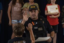 Officer Davey Silva, a police officer with Marine Corps Base Hawaii Provost Marshals Office, congratulates a student during a Drug Abuse Resistance Education graduation ceremony at Mokapu Elementary, MCBH, April 5, 2024. Officers with MCBH PMO visited the school over the span of ten weeks to educate fifth-grade students on the harmful effects of drug and alcohol abuse through the D.A.R.E Program. (U.S. Marine Corps photo by Lance Cpl. Hunter Jones)