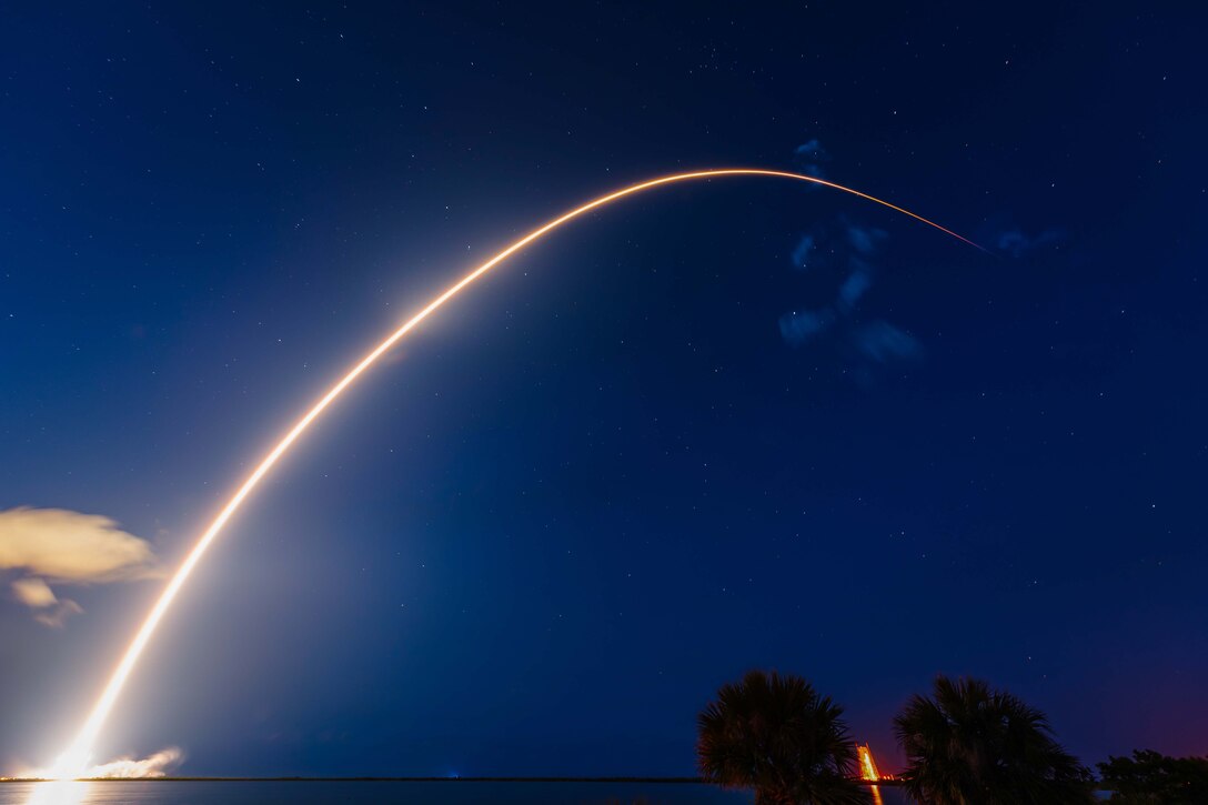 A rocket flies across a darkened sky.