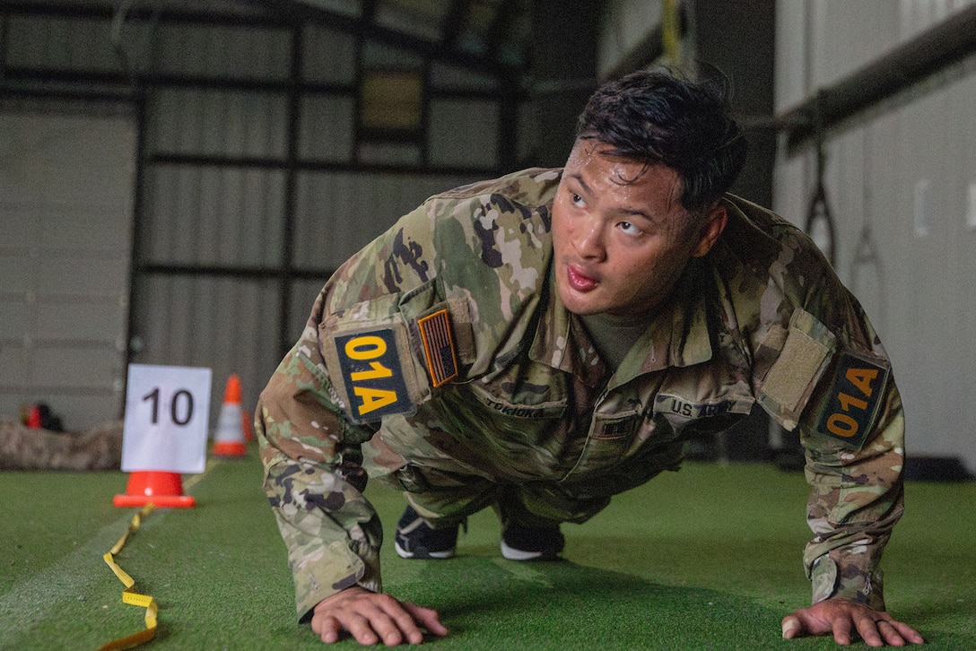 A uniformed soldier sweats while doing pushups during a competition.