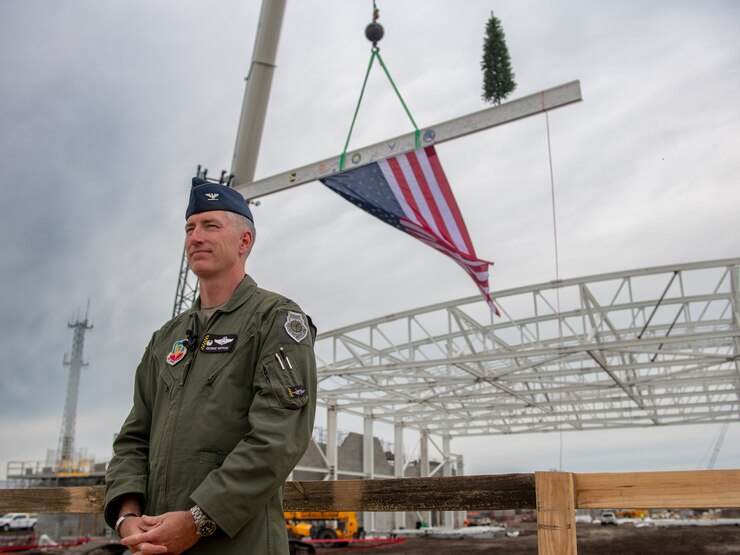 A man stands next to a support beam with an American flag