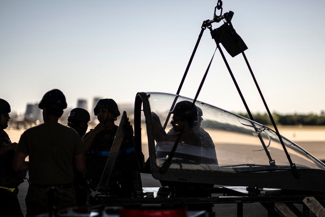 Airmen conducting maintenance around an aircraft canopy