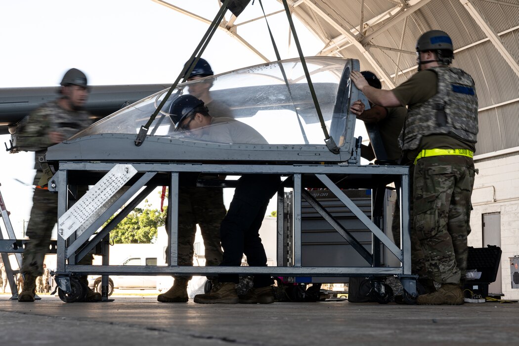 Airmen conducting maintenance around an aircraft canopy