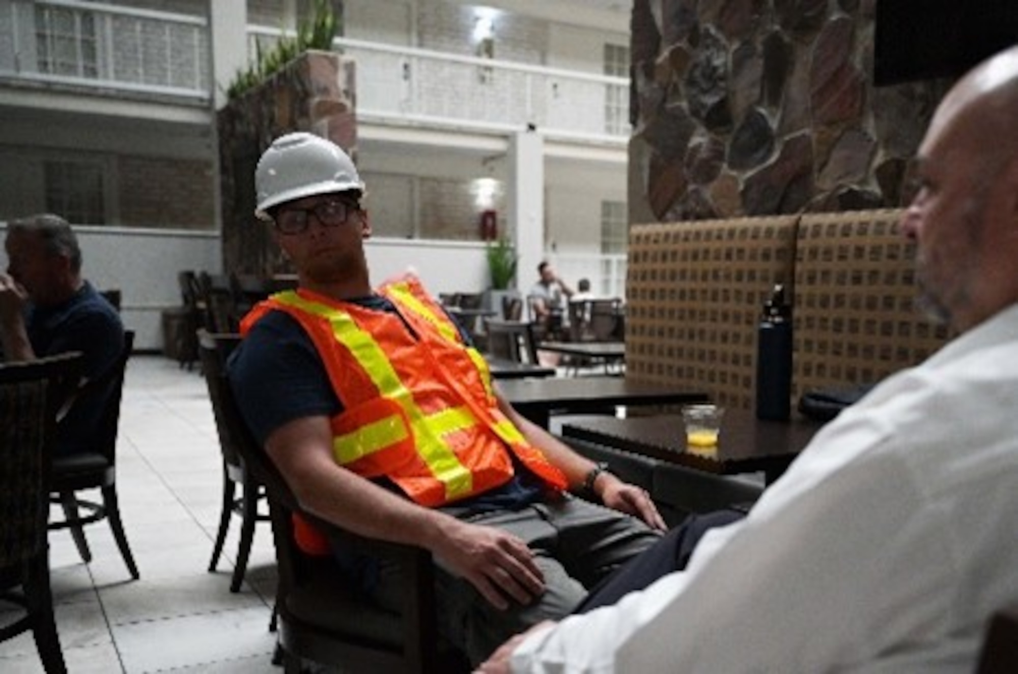 People sitting at a table one wearing construction gear.