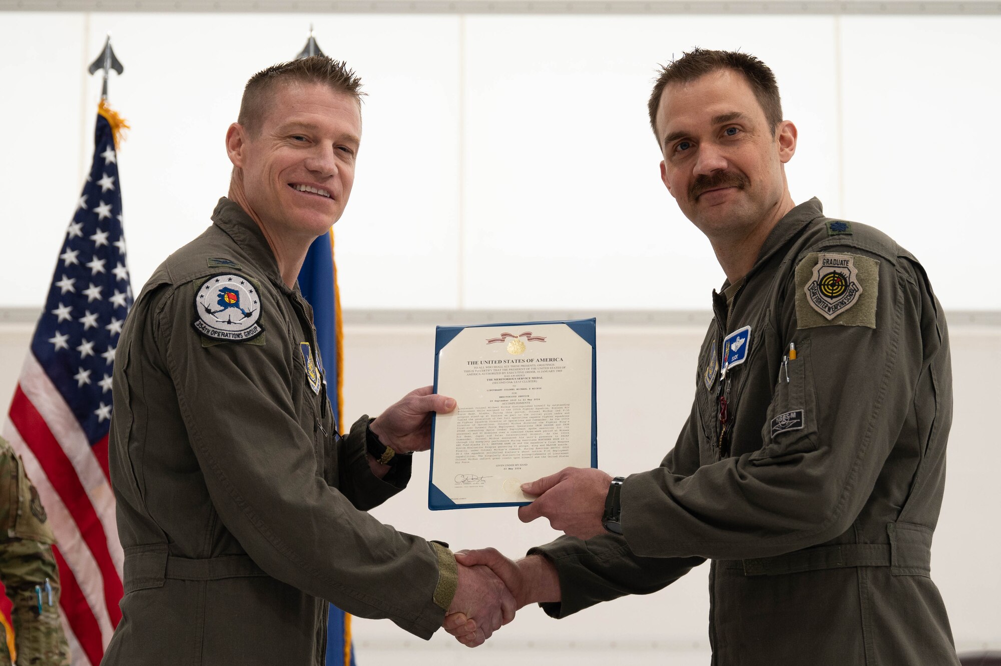 U.S. Air Force Col. Curtis Dougherty (left), 354th Operations Group commander, awards the Meritorious Service Medal to Lt. Col Michael Mickus, 355th Fighter Squadron outgoing commander, during a change of command ceremony at Eielson Air Force Base, Alaska, May 17, 2024.