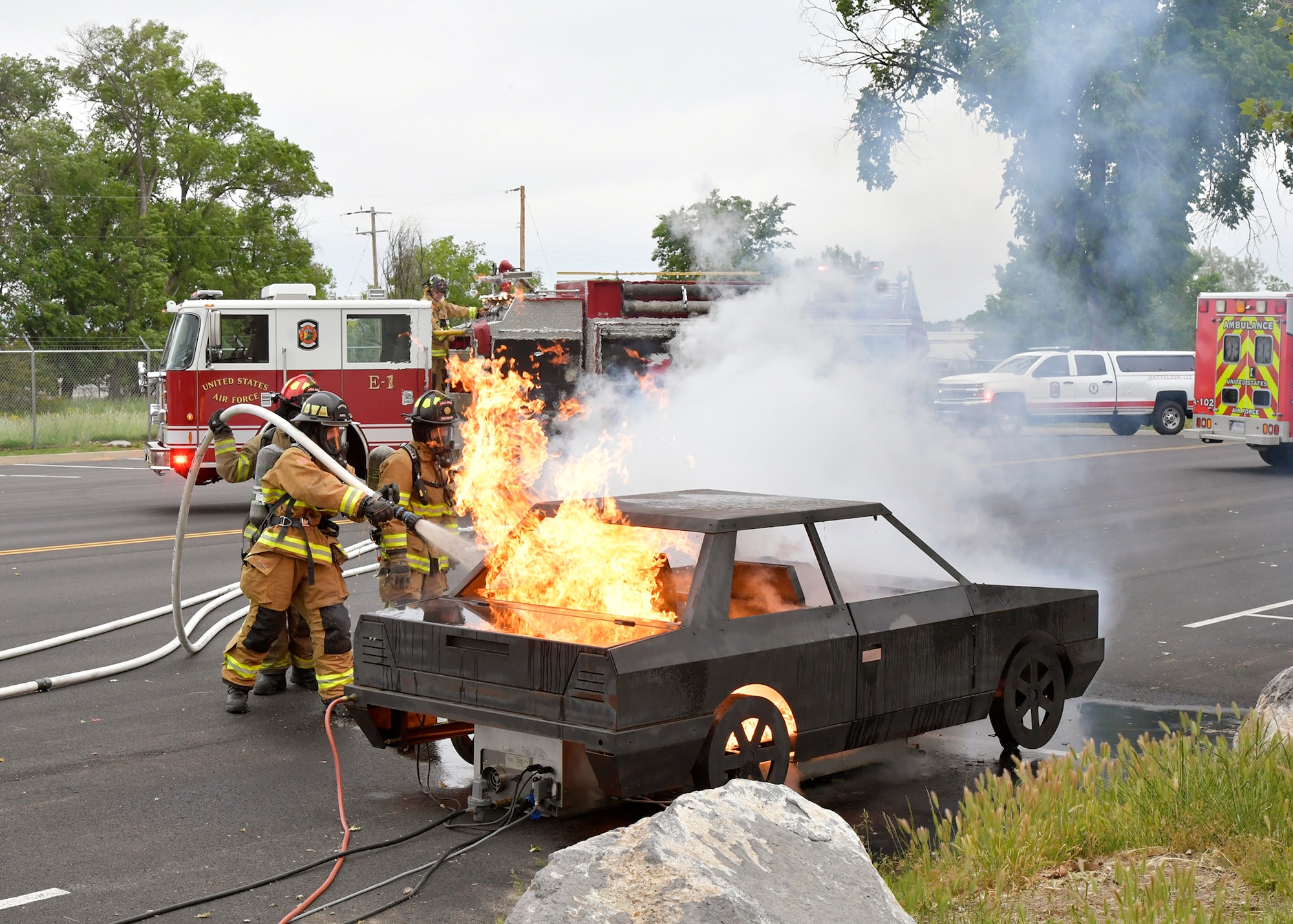 Three firefighters tackle a simulated car fire blaze