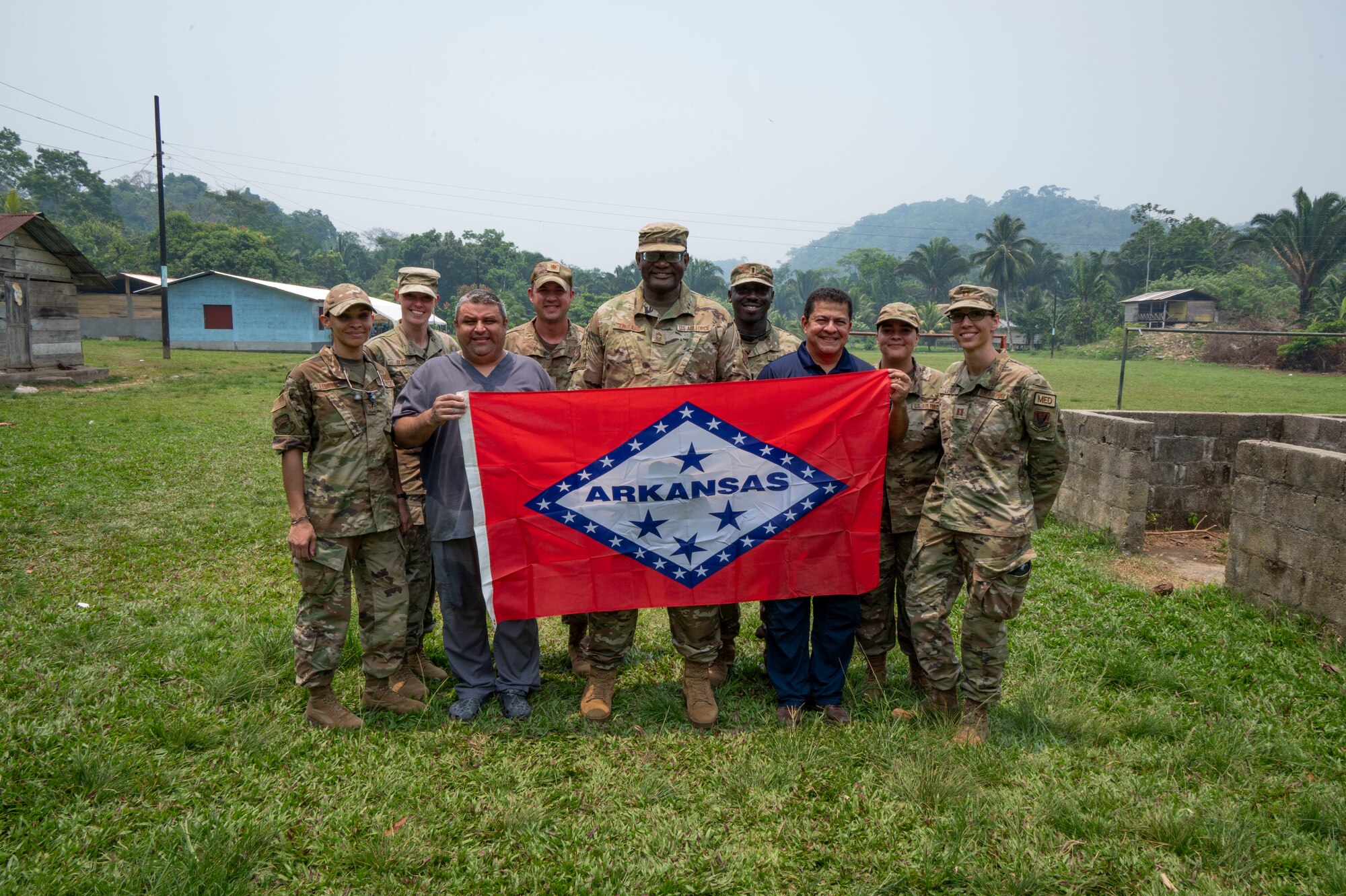 A group of people holding an Arkansas state flag.