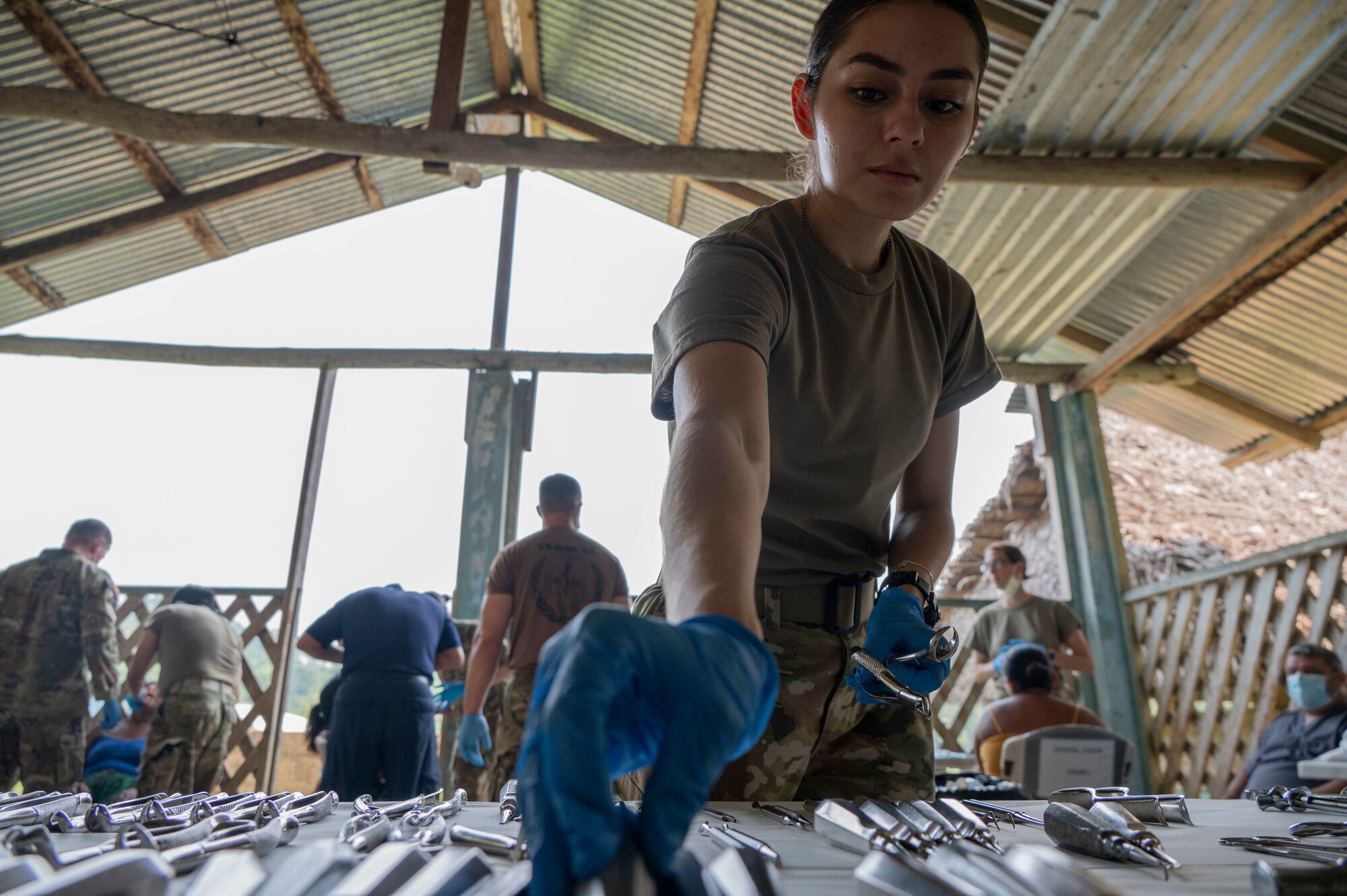 A photo of a woman reaching to grab a dental instrument.