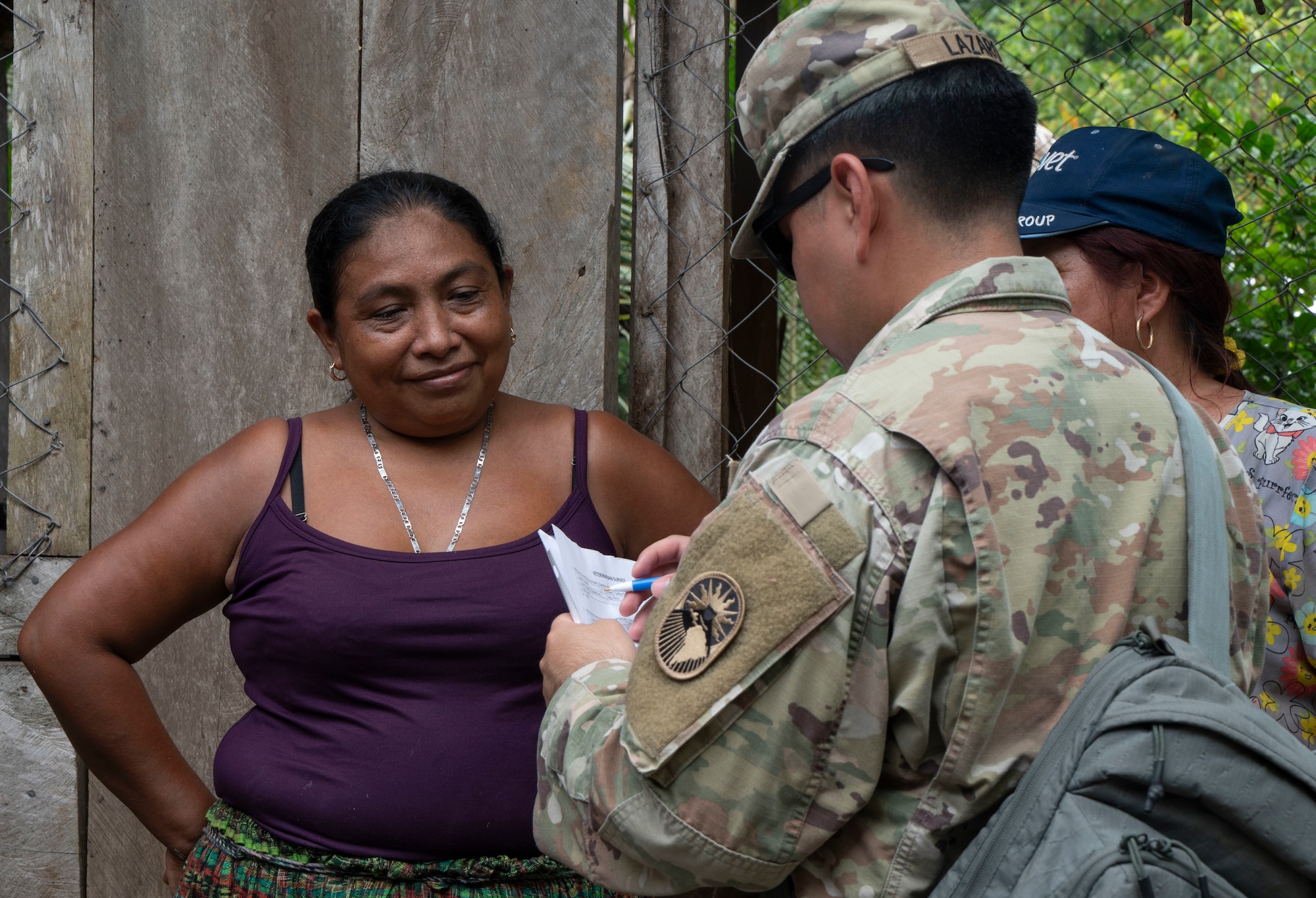 A photo of a woman smiling at a U.S. military member talking to her.