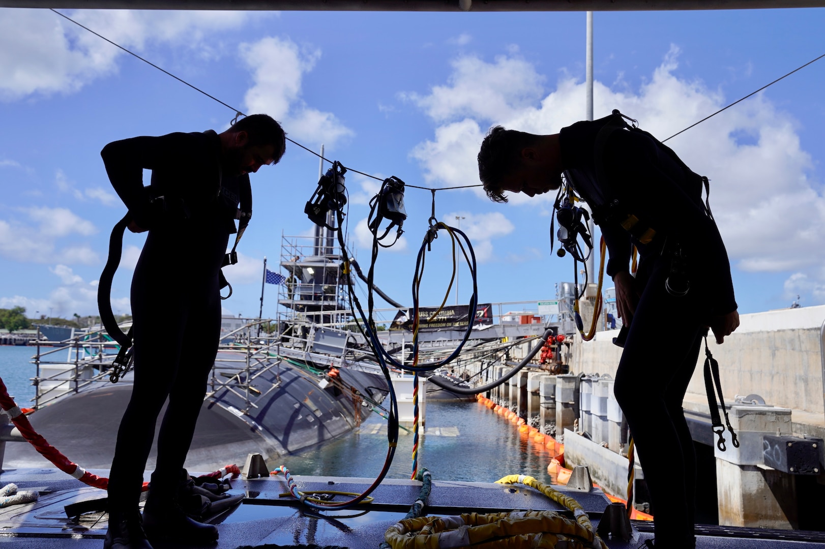 Royal Australian Navy divers don their equipment before entering the water during a familiarization dive with Pearl Harbor Naval Shipyard and Intermediate Maintenance Facility