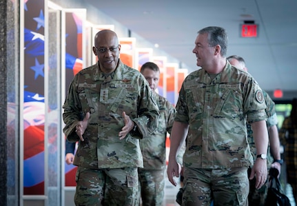 Two men in military uniform walk down a hall. Other service members walk behind them.
