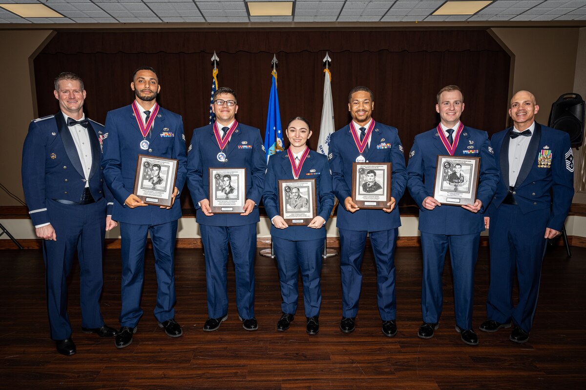 A group photo of Airmen holding award plaques with two leadership personnel.