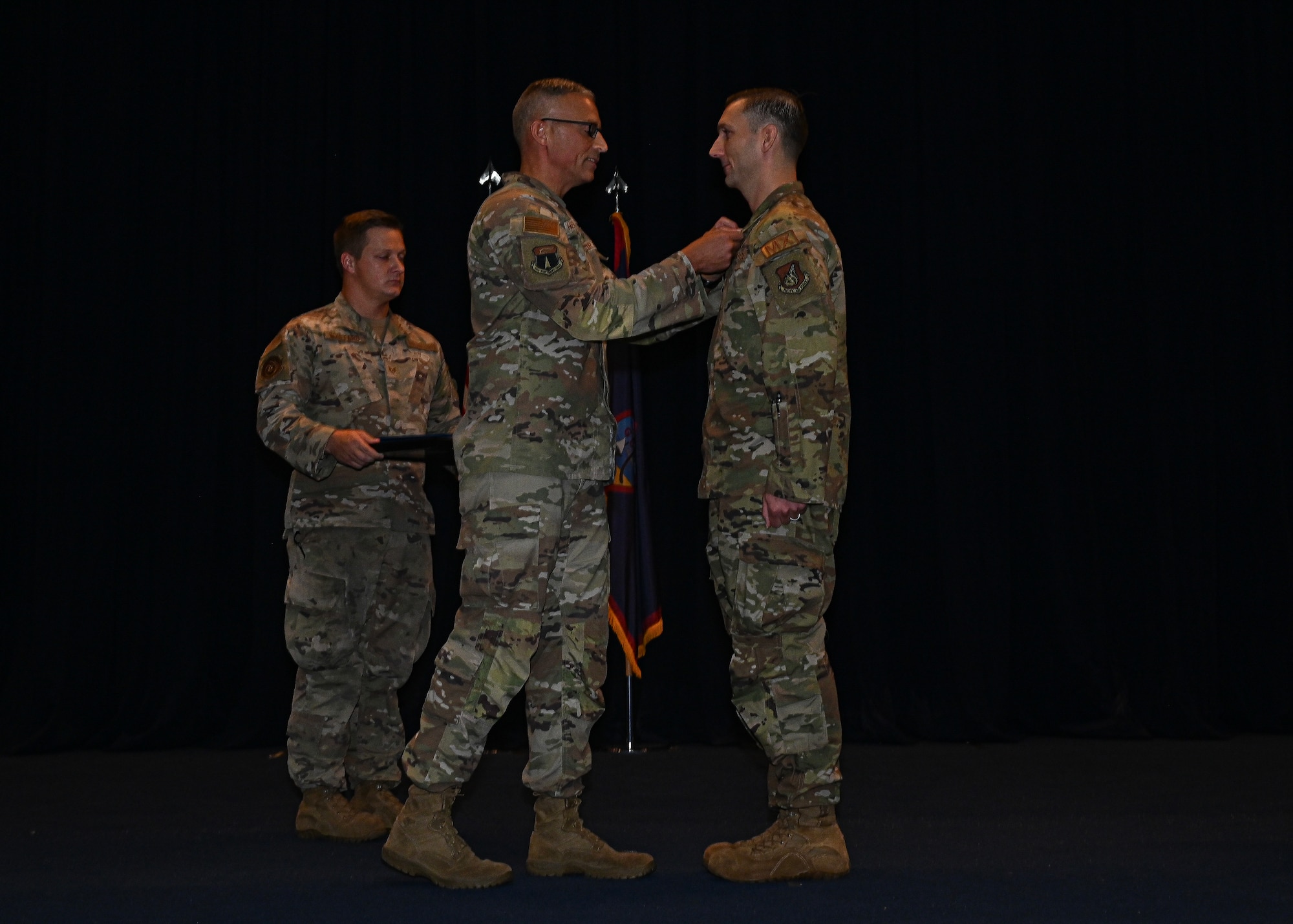 The 36th Maintenance Group commander, placed a medal on the outgoing 36th Maintenance Squadron commander while facing him on stage.