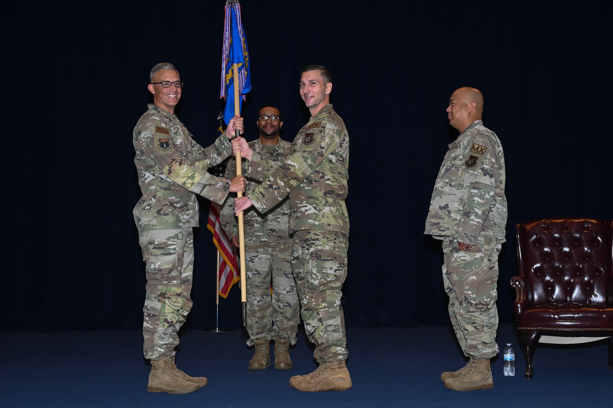 The 36th Maintenance Group commander holds the guidon flag on stage with the outgoing 36th Maintenance Squadron commander.