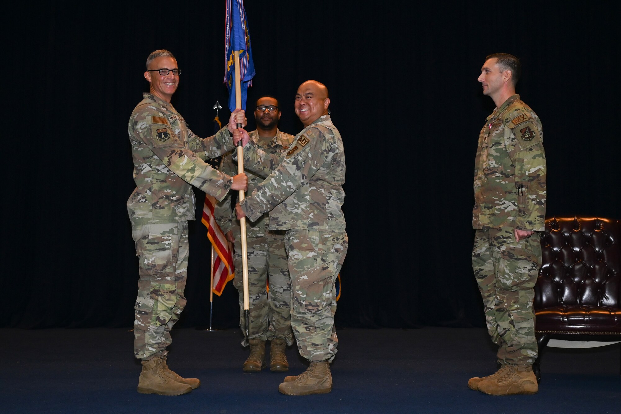 The 36th Maintenance Group commander holds the guidon flag on stage with the new 36th Maintenance Squadron commander.