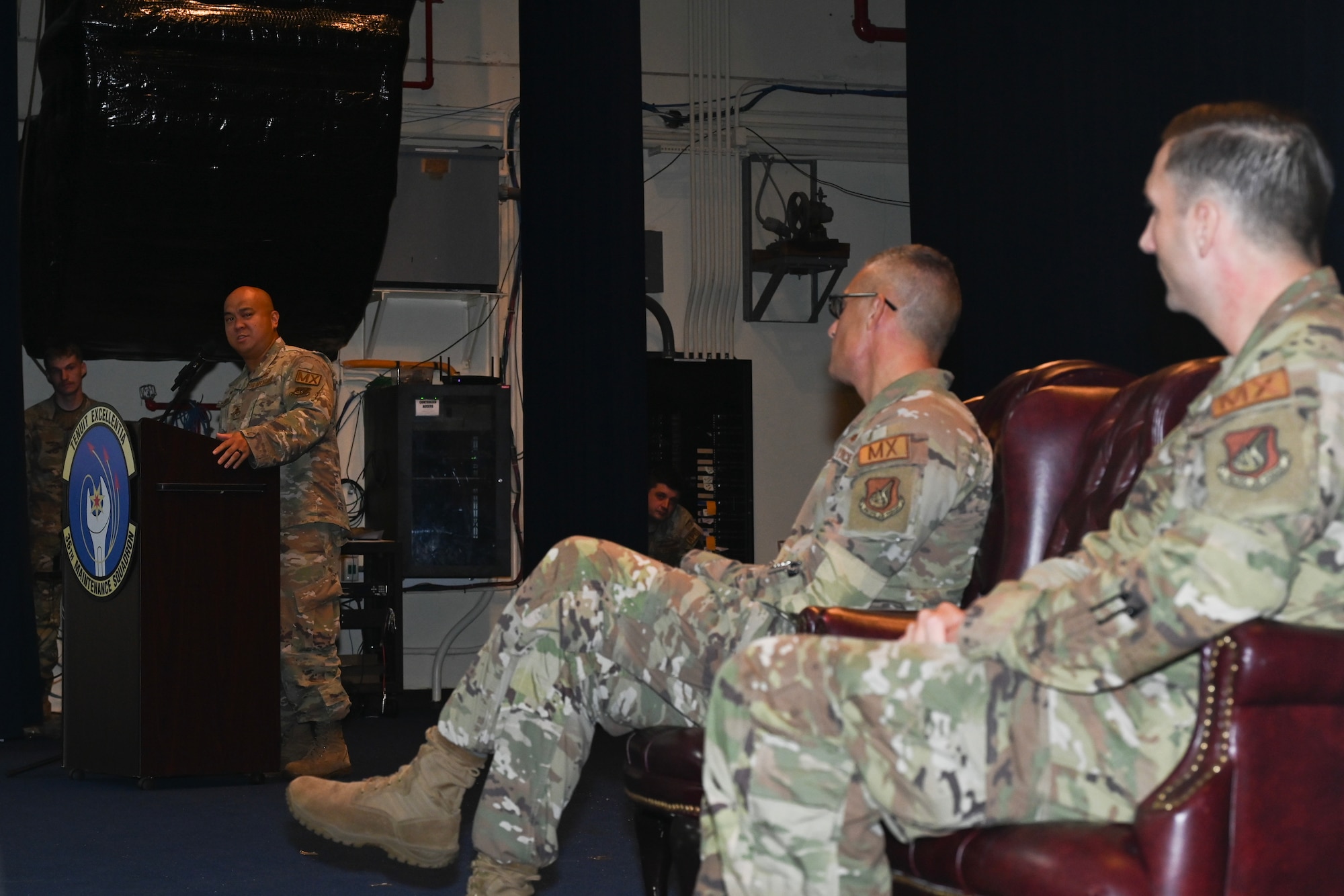 The new 36th Maintenance Squadron commander speaks 36th Maintenance Group commander and outgoing commander, all of whom are on stage.