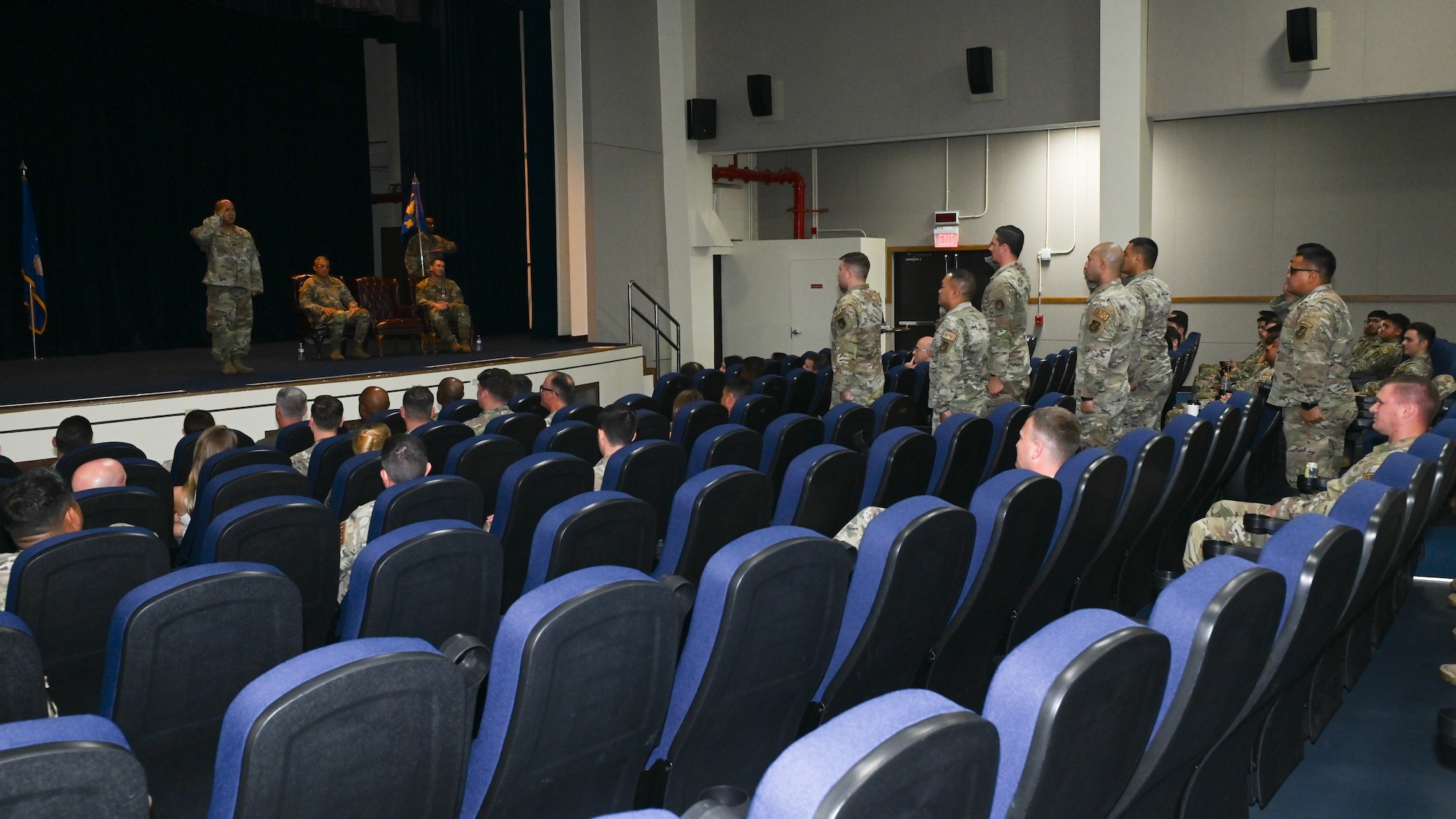36th Maintenance Squadron Airmen salute their new commander who is standing on stage saluting them back.