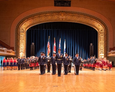 military members, pipe bands and Irish dance groups stand in formation in auditorium