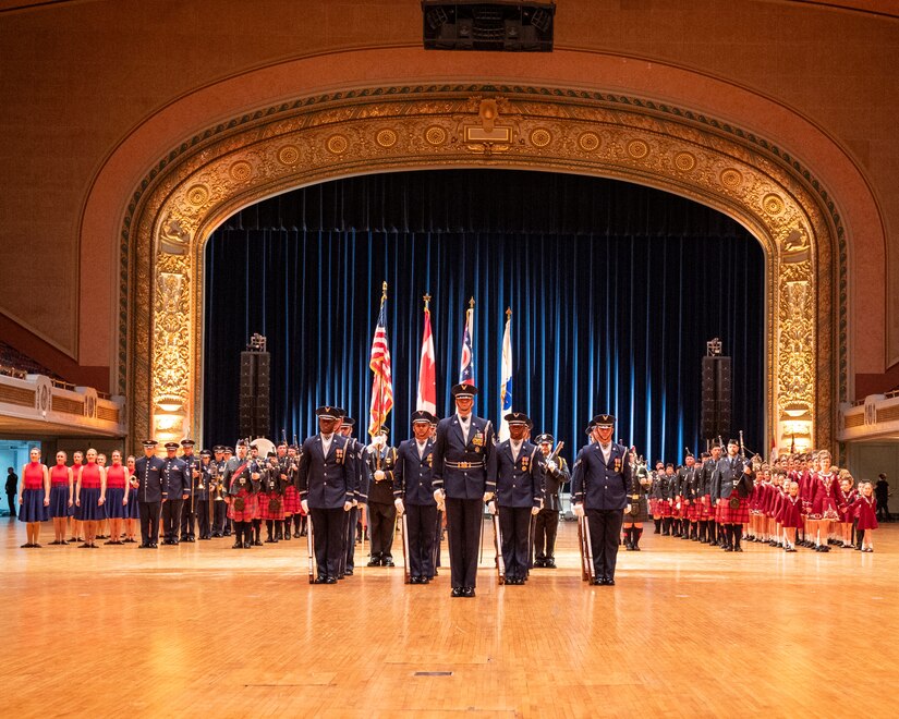 military members, pipe bands and Irish dance groups stand in formation in auditorium