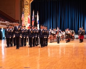 military members stand in formation in an auditorium