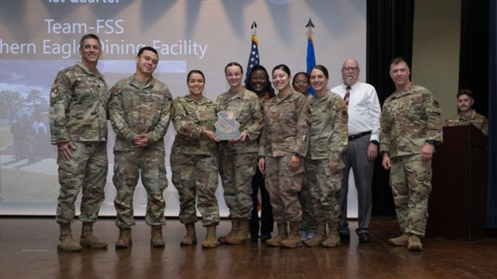 U.S. Air Force Lt. Col. James Melvin, left, Mission Support Group deputy commander, and Chief Master Sgt. Edward Mueller, right, Mission Support Group senior enlisted leader, presents Southern Eagles Dining Facility, center, Team of the First Quarter Award at Seymour Johnson Air Force Base, North Carolina, April 19, 2024. The ceremony recognized the award winners for their exceptional leadership during the first quarter. (U.S. Air Force photo by Airman Megan Cusmano)
