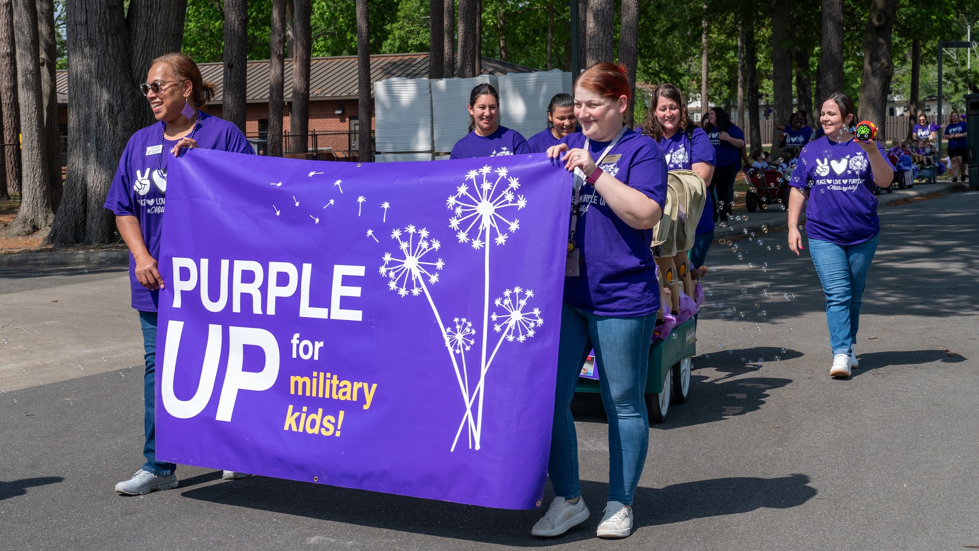 Employees of the Seymour Johnson Child Development Center participate in the annual “Purple Up Parade” at Seymour Johnson Air Force Base, North Carolina, April 19, 2024. The color purple is used as a symbol of support and unity for all military children. (U.S. Air Force Photo by Airman Rebecca Tierney)