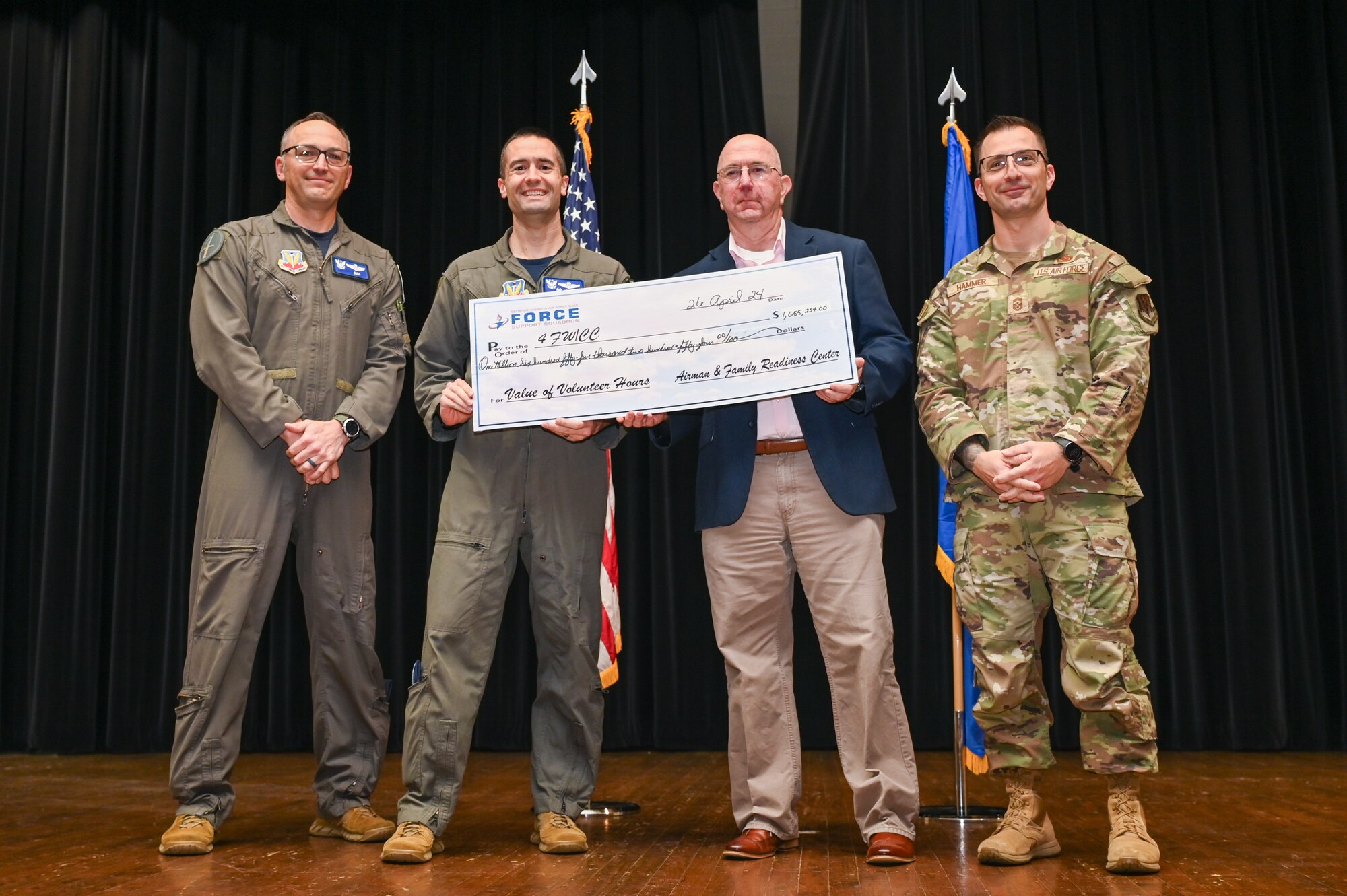 Jeff Craver, center right, Military and Family Readiness Center flight chief, presents a check to Col. Morgan Lohse, center left, 4th Fighter Wing commander, during a volunteer appreciation ceremony at Seymour Johnson Air Force Base, North Carolina, April 26, 2024. This check represents the hours Seymour Johnson’s volunteers have completed in 2023, which has the monetary equivalence of $1,655,254. (U.S. Air Force photo by Airman Rebecca Tierney)