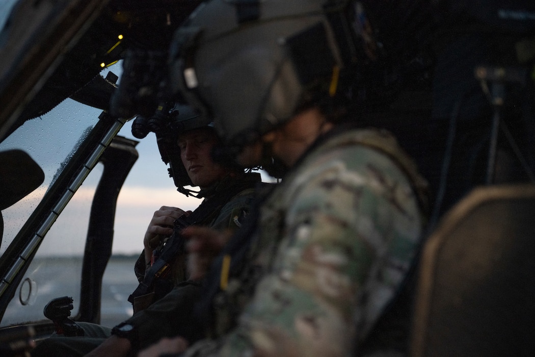 A photo of two pilots sitting in the cock pit of a helicopter.