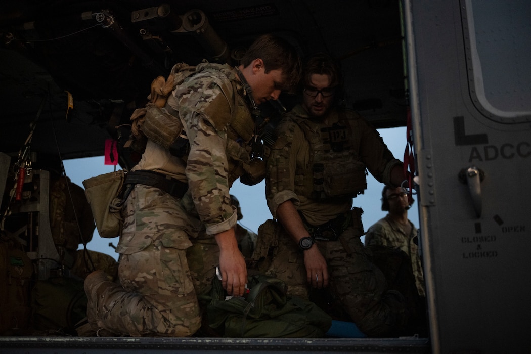 A photo of two Airmen kneeling down in the back of a helicopter organizing medical equipment.
