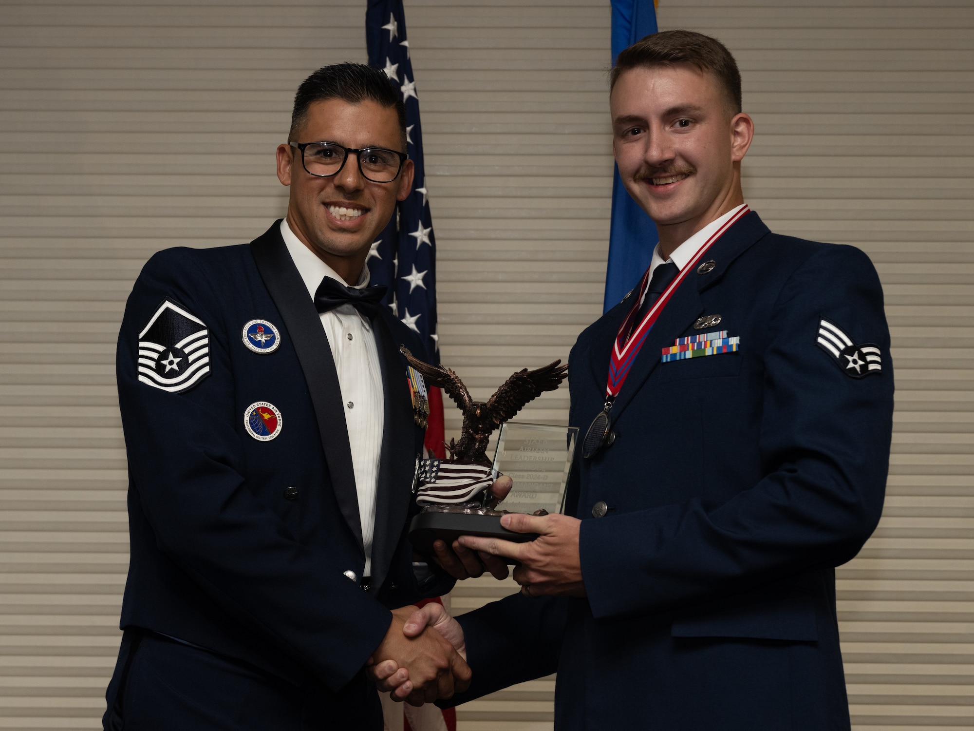 U.S. Air Force Senior Airman Ashton Neil, 4th Component Maintenance Squadron aerospace propulsion tech, right, receives the Commandant’s Award from Master Sgt. Mark Benevides, Airman Leadership School instructor, during the ALS class 24-D graduation ceremony at Seymour Johnson Air Force Base, North Carolina, May 2, 2024. The Commandant’s Award is presented to an ALS graduate that possessed the highest degree of character, competence and commitment during the ALS course. (U.S. Air Force photo by Airman Megan Cusmano)