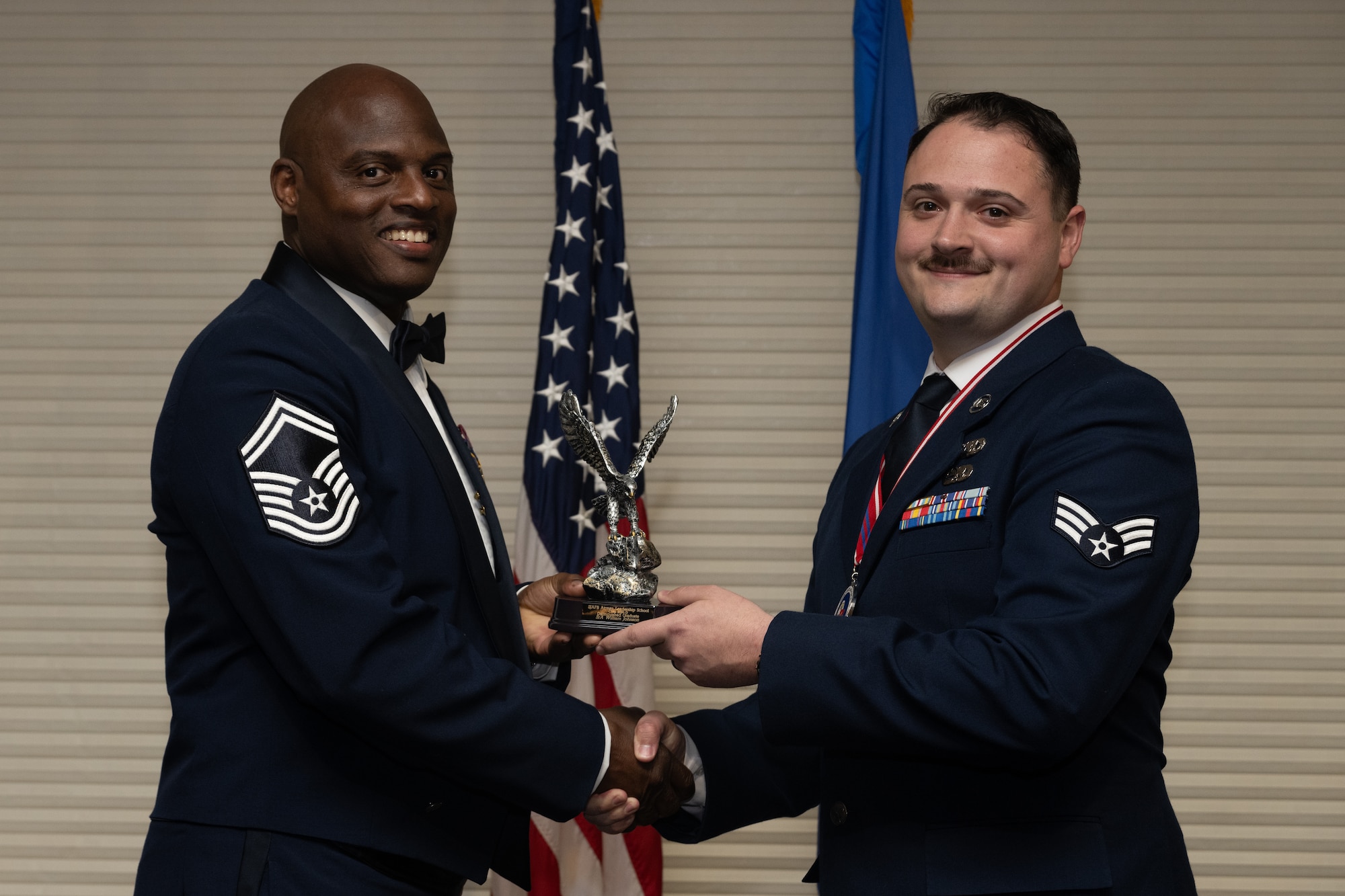 U.S. Air Force Senior Airman William Johnson, 4th Munitions Squadron training technician, receives the Distinguished Graduate Award from Senior Master Sgt. Torrey Byrd, Maintenance Operations flight weapons superintendent, during the Airman Leadership School class 24-D graduation ceremony at Seymour Johnson Air Force Base, North Carolina, May 2, 2024. Students who received the Distinguished Graduate Award displayed effective teamwork, academic excellence and leadership skills. (U.S. Air Force photo by Airman Megan Cusmano)