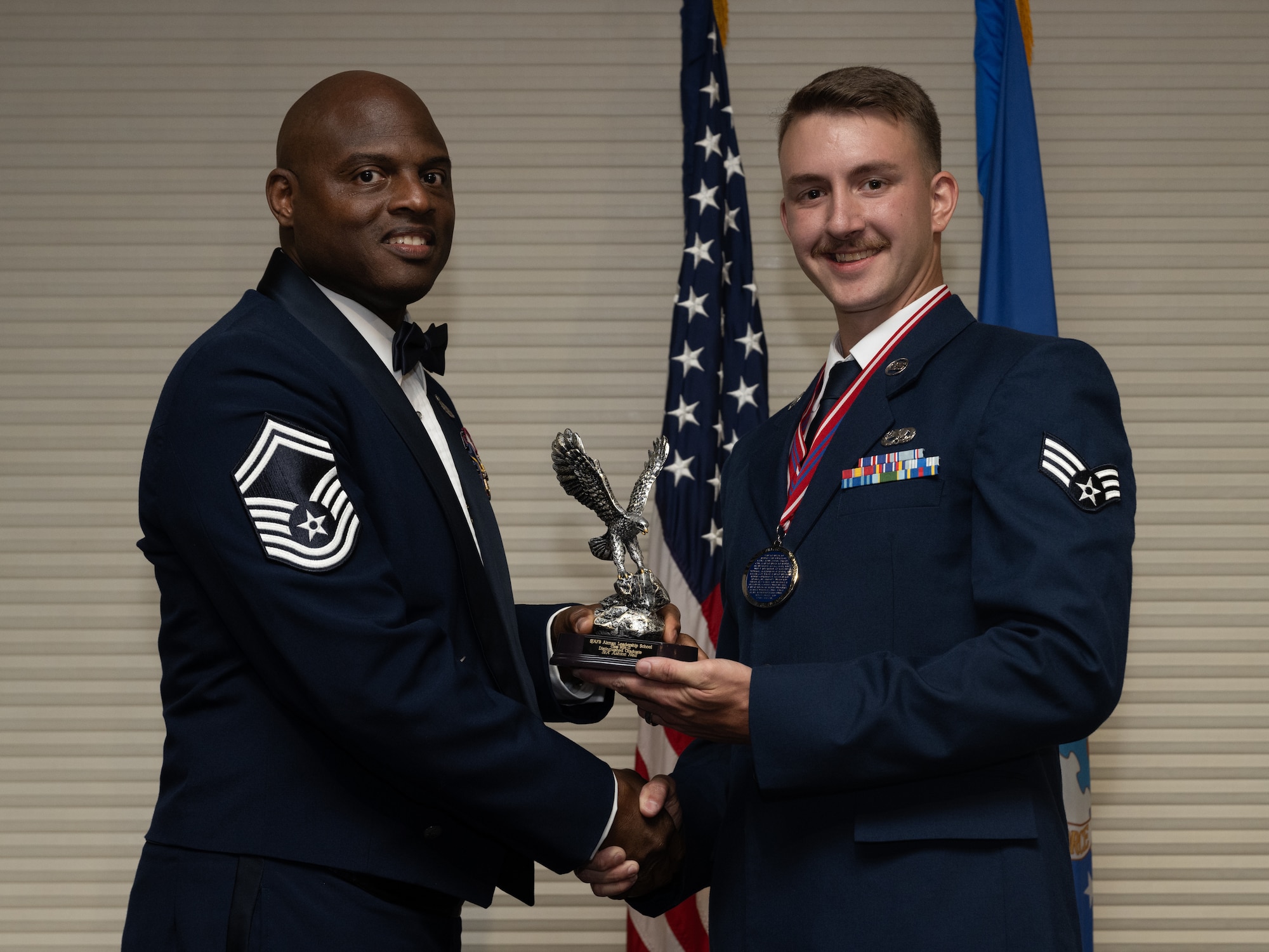 U.S. Air Force Senior Airman Ashton Neil, 4th Component Maintenance Squadron aerospace propulsion tech, receives the Distinguished Graduate Award from Senior Master Sgt. Torrey Byrd, Maintenance Operations flight weapons superintendent, during the Airman Leadership School class 24-D graduation ceremony at Seymour Johnson Air Force Base, North Carolina, May 2, 2024. Students who received the Distinguished Graduate Award displayed effective teamwork, academic excellence and leadership skills. (U.S. Air Force photo by Airman Megan Cusmano)