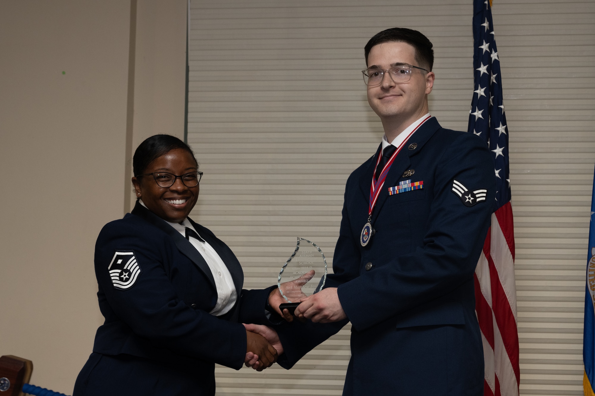 U.S. Air Force Senior Airman Matthew Fox, 4th Component Maintenance Squadron avionics journeyman, receives the Academic Achievement Award from Master Sgt. Kahlia Rainer, 4th Medical group 1st sergeant, during the Airman Leadership School class 24-D graduation ceremony at Seymour Johnson Air Force Base, North Carolina, May 2, 2024. The student presented with the Academic Achievement Award maintained the highest grade point average throughout the ALS course. (U.S. Air Force photo by Airman Megan Cusmano)