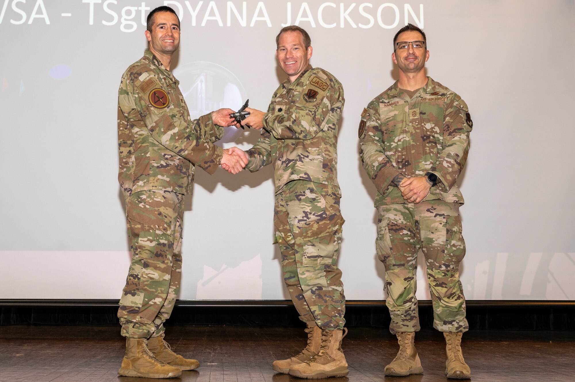 U.S. Air Force Lt. Col. Nathan Mayenschein, center, 4th Wing Staff Agency staff judge advocate, accepts the Non-Commissioned Officer of the 1st Quarter Award on behalf of Tech. Sgt. Dyana Jackson, 4 WSA Non-Commissioned Officer in Charge of military justice, from Col. Morgan Lohse, left, 4th Fighter Wing commander and Chief Master Sgt. Paul Hammer, right, 4 FW command chief, during the 4 FW 1st Quarter Awards ceremony at Seymour Johnson Air Force Base, North Carolina, May 3, 2024. Quarterly Awards are awarded to Airmen and civilians in 13 different categories including Airman of the Quarter, Key Spouse of the Quarter and many more. (U.S. Air Force photo by Airman Rebecca Tierney)