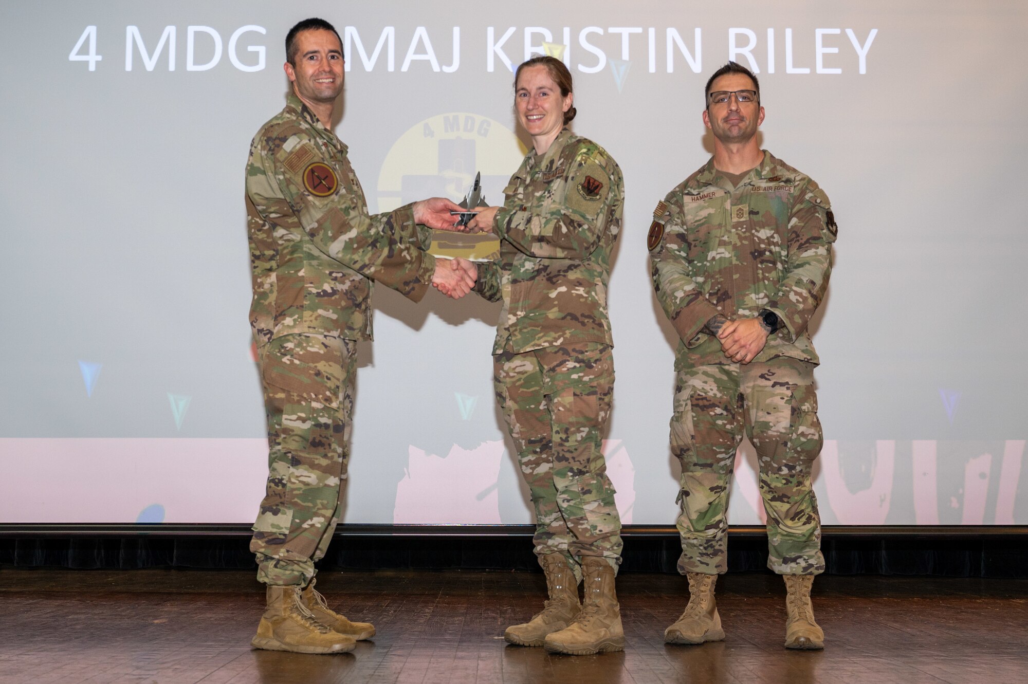 U.S. Air Force Maj. Kristin Riley, center, 4th Medical Group pharmacy commander, receives the Field Grade Officer of the 1st Quarter Award from Col. Morgan Lohse, left, 4th Fighter Wing commander and Chief Master Sgt. Paul Hammer, right, 4 FW command chief, during the 4 FW 1st Quarter Awards ceremony at Seymour Johnson Air Force Base, North Carolina, May 3, 2024. Quarterly Awards are awarded to Airmen and civilians in 13 different categories including Airman of the Quarter, Key Spouse of the Quarter and many more. (U.S. Air Force photo by Airman Rebecca Tierney)