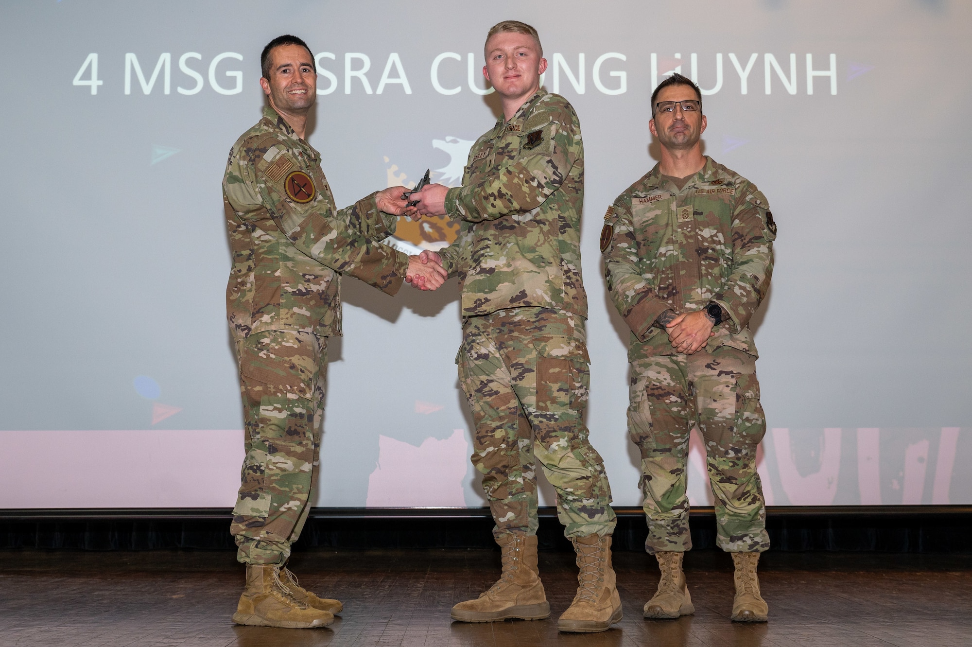 U.S. Air Force 2d Lt. Hunter Bailey, center, 4th Contracting Squadron contracting specialist accepts the Volunteer of the 1st Quarter Award on behalf of Senior Airman Cuong Huynh, 4th Mission Support Group contracting officer, from Col. Morgan Lohse, left, 4th Fighter Wing commander and Chief Master Sgt. Paul Hammer, right, 4 FW command chief, during the 4 FW 1st Quarter Awards ceremony at Seymour Johnson Air Force Base, North Carolina, May 3, 2024. Quarterly Awards are awarded to Airmen and civilians in 13 different categories including Airman of the Quarter, Key Spouse of the Quarter and many more. (U.S. Air Force photo by Airman Rebecca Tierney)