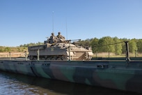 The Warrior, a British armored vehicle, crosses the Drawa River on an Improved Ribbon Bridge during DEFENDER 24 at Drawsko Combat Training Center, Poland, May 16, 2024. The high concentration of waterways and water obstacles in the European region have led to the demand for wet gap crossings to be implemented into various NATO exercises. (U.S. Army photo by Capt. Michael Mastrangelo)