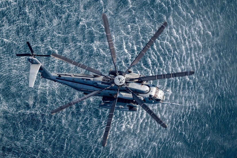 A helicopter hovers above the ocean.