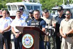 A Coast Guard Lt. Cmdr. speaks to a group in front of a podium.