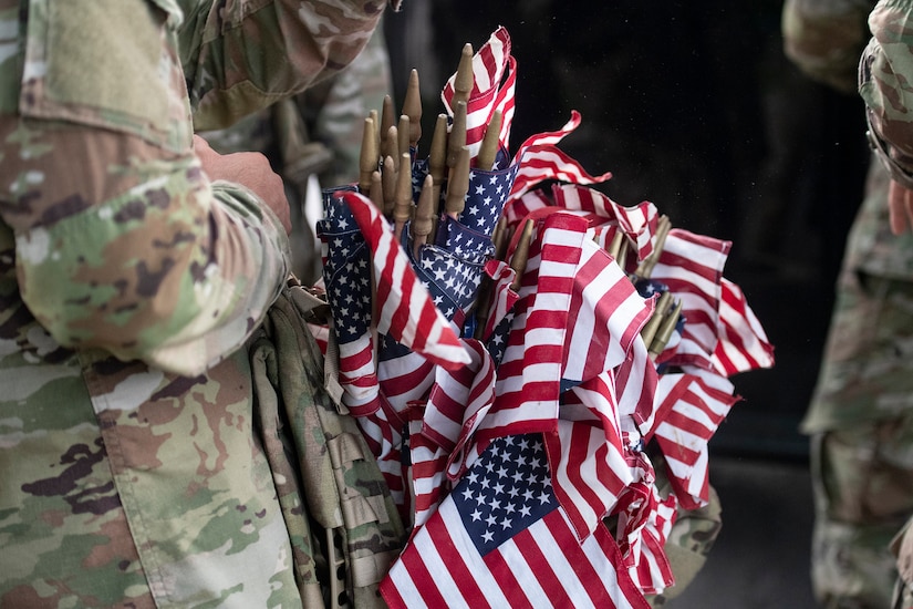 A soldier holds small U.S. flags.