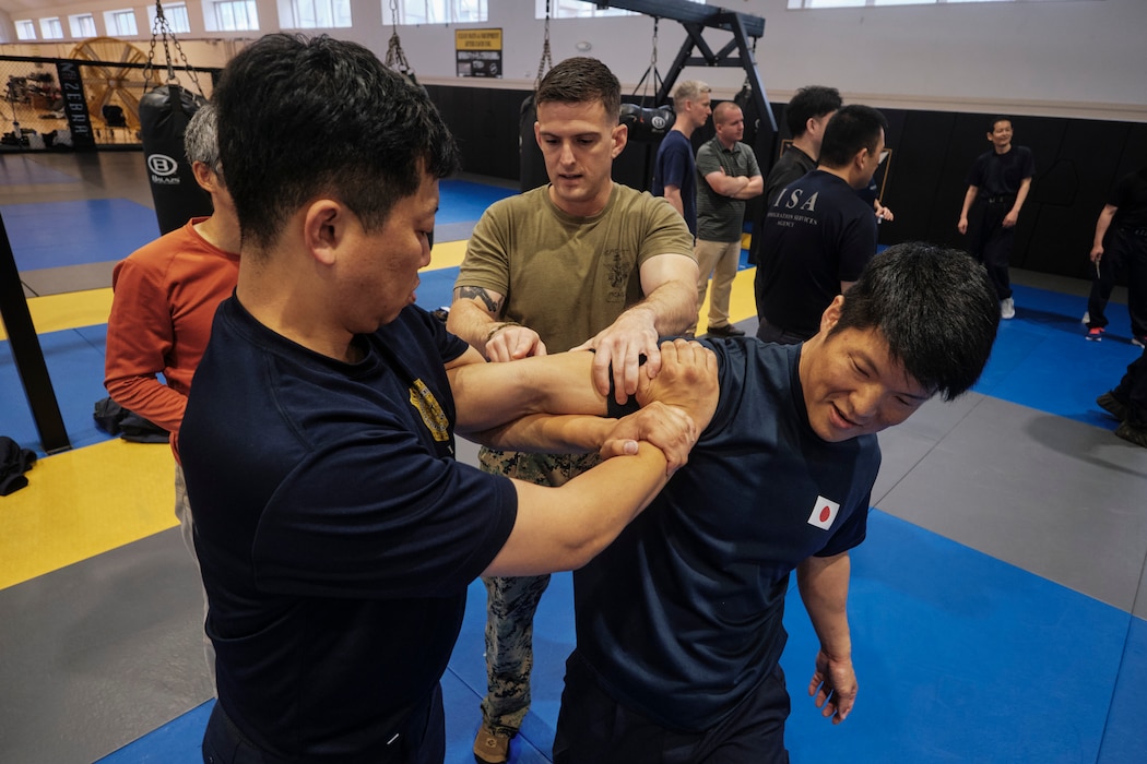 Sgt. Peyton Capone from Yokosuka's Fleet Anti-Terrorism Security Team Company Pacific (FASTPAC) coaches two agents from the Government of Japan's Immigration Services Agency (ISA) during a martial arts exchange May 14 at Commander, Fleet Activities Yokosuka's Hawk's Nest.